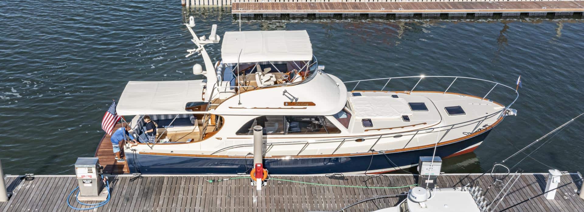 White and blue sailing motor yacht named Darling docked in a marina