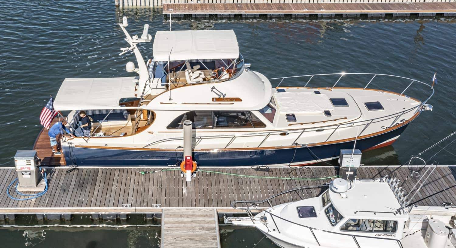 White and blue sailing motor yacht named Darling docked in a marina